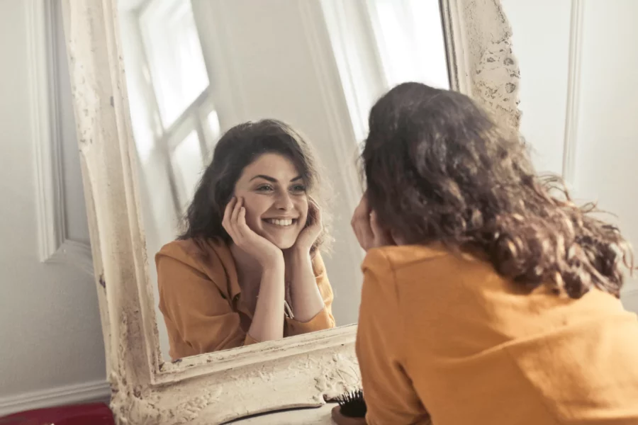 Woman with a positive attitude smiling in the mirror